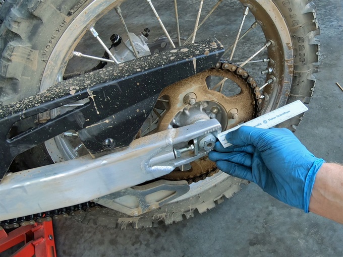 Measuring between adjuster plate and swingarm end to verify wheel alignment - KLX140L
