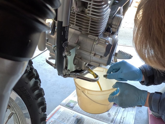Oil draining from KLX140L after engine oil drain plug removed