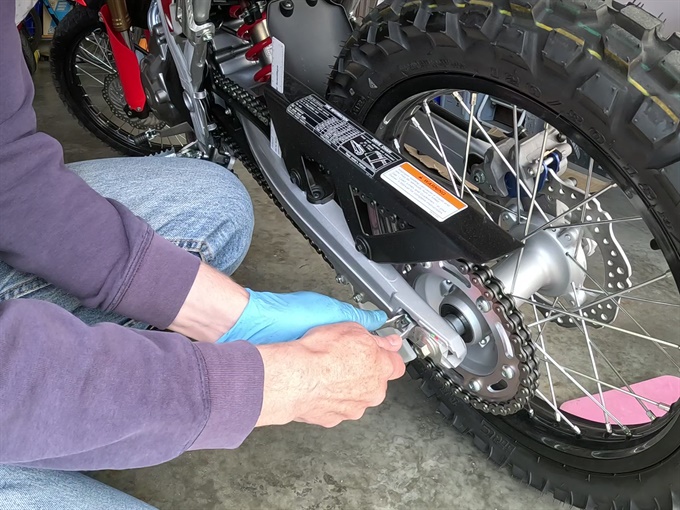 Loosening the chain adjuster locknuts on CRF300L (left side)