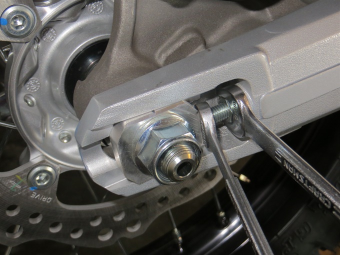 Loosening the chain adjuster locknuts on CRF300L (right side)