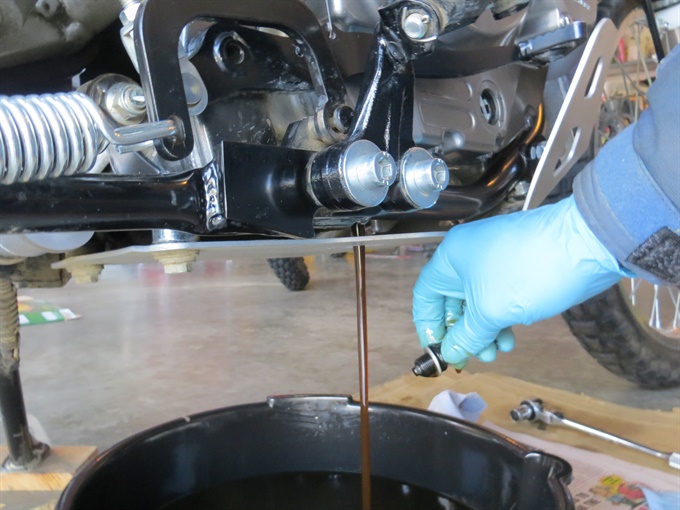 Oil draining from DR650SE after engine oil drain plug removed