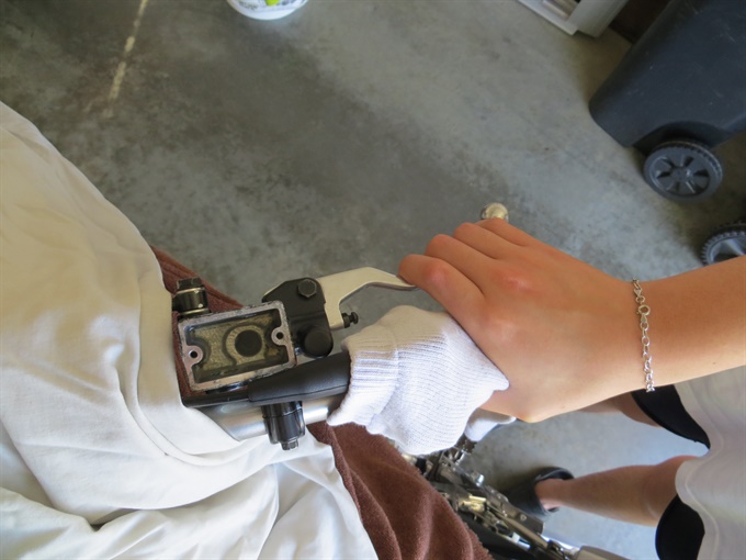 Squeezing the front brake level with fresh brake fluid in reservoir (KLX140L).