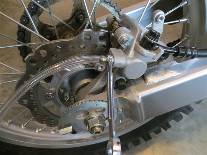 CRF250F rear brake caliper with guard removed and bleed hose attached.